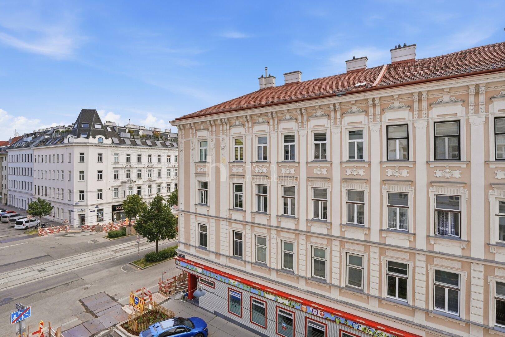 Historisches Wohngebäude mit klassischer Fassade und Blick auf die belebte städtische Umgebung und Straße.