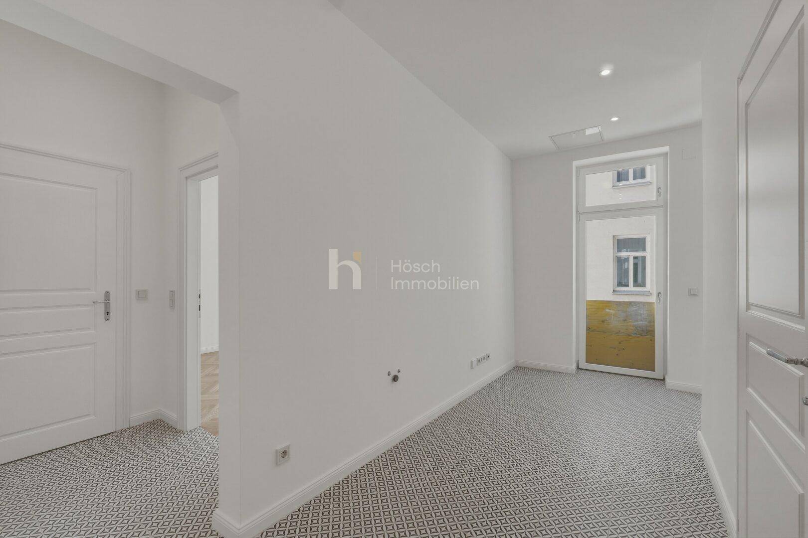 Heller Flur mit modernem Fliesenboden und Zugang zu einem Außenbereich.