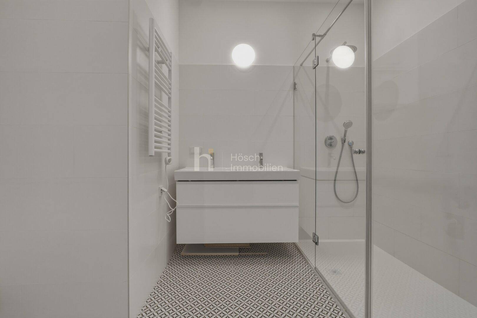 Modernes Badezimmer mit ebenerdiger Dusche, stilvollem Waschtisch und Handtuchheizkörper.