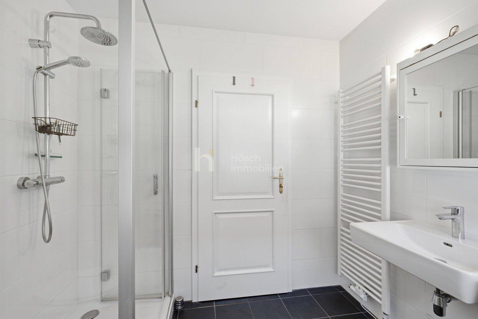 Helles Badezimmer mit Duschkabine, Einzelwaschbecken und einem beheizten Handtuchhalter.
