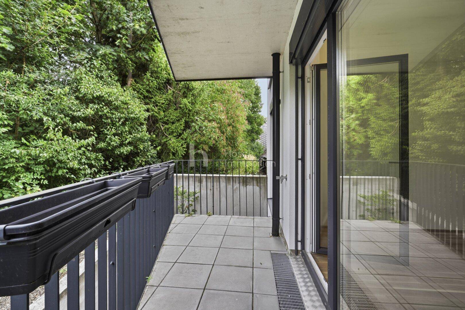 Geräumiger Balkon mit Fliesenboden und Blick auf üppiges Grün, ideal zum Entspannen.