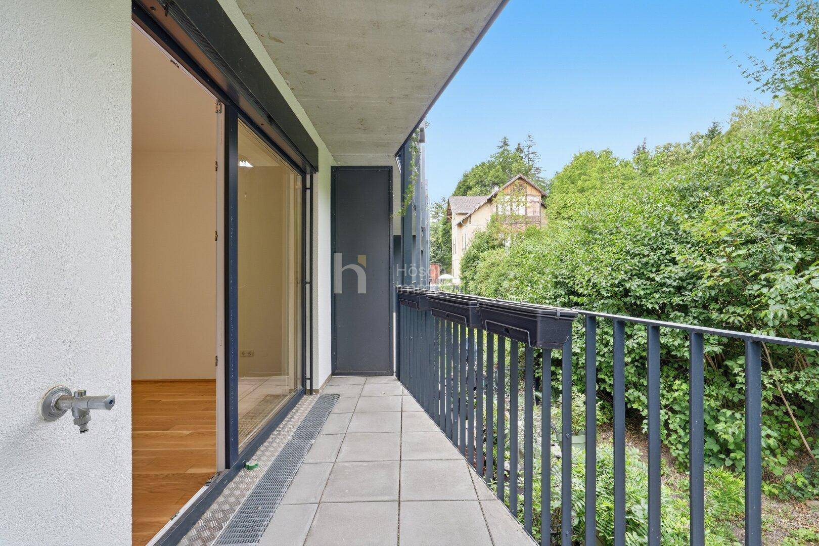 Geräumiger Balkon mit Fliesenboden und Blick auf üppiges Grün, ideal zum Entspannen.