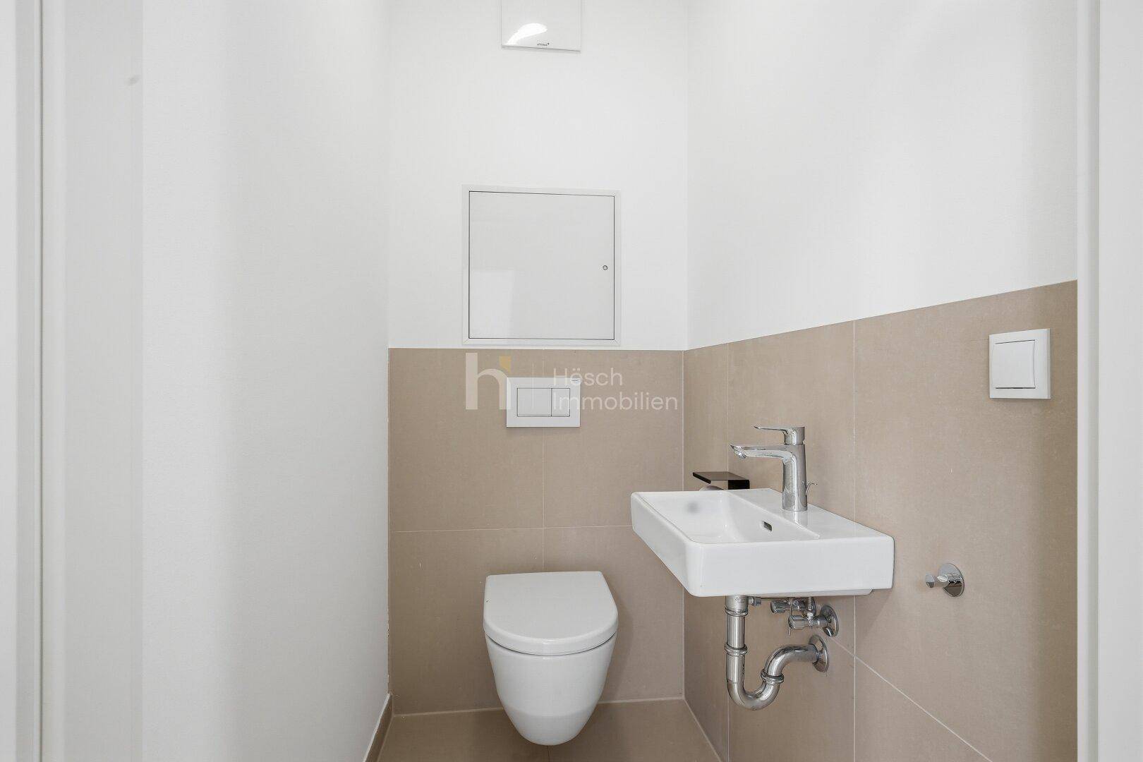 Modernes Gäste-WC mit wandhängender Toilette und kleinem Handwaschbecken.