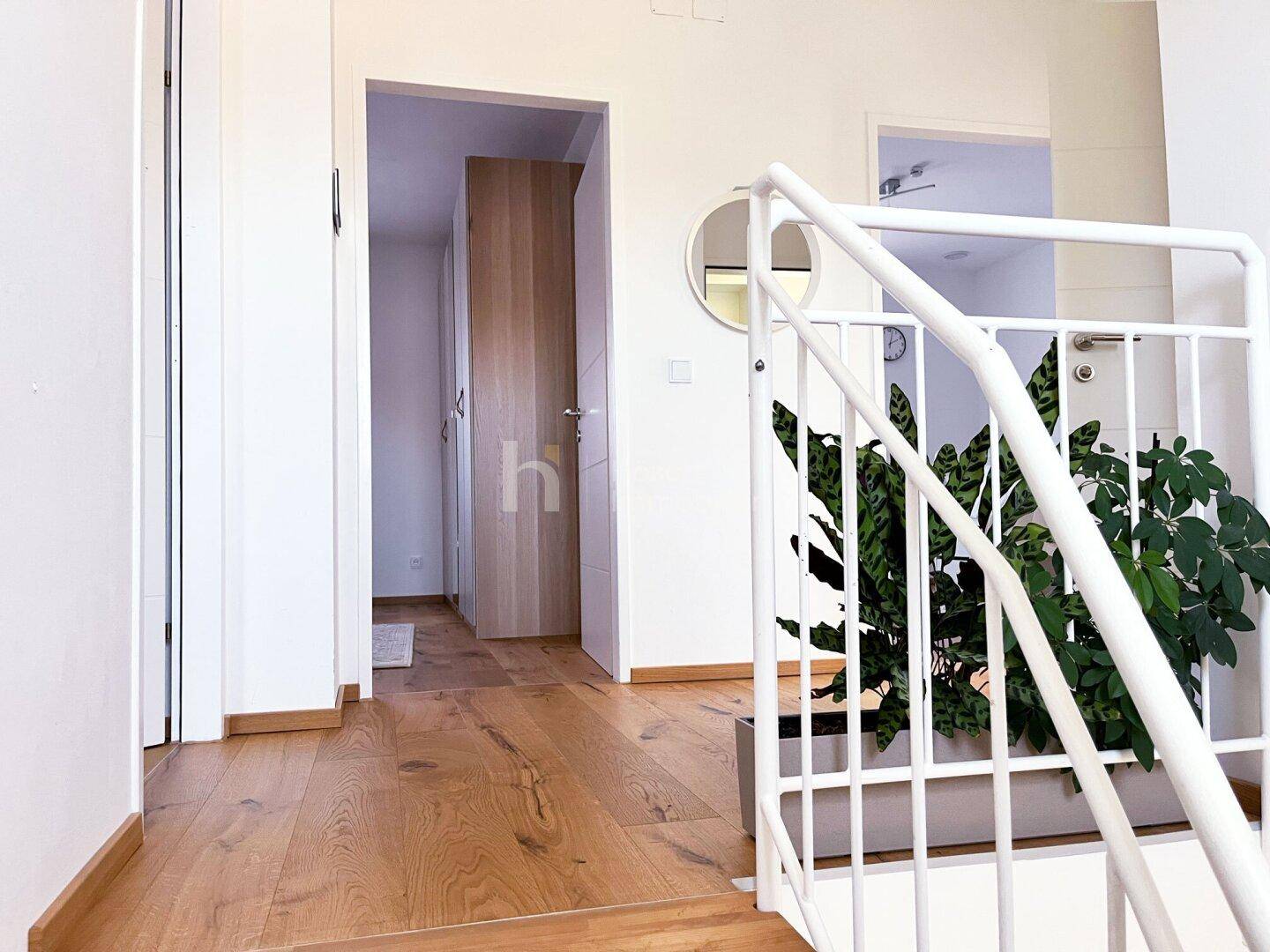 Heller Flur im Obergeschoss mit Holzboden und modernem Treppengeländer.