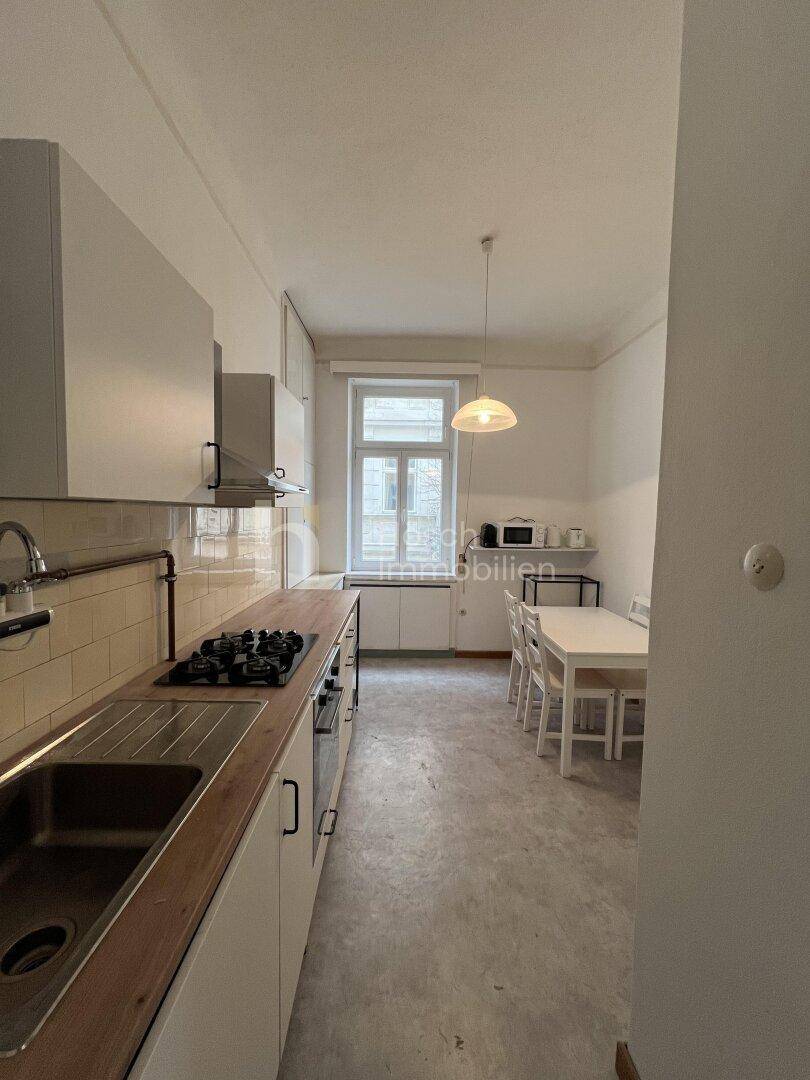 Funktionale Küche mit Gasherd, Holz-Arbeitsplatte und Essbereich am Fenster.