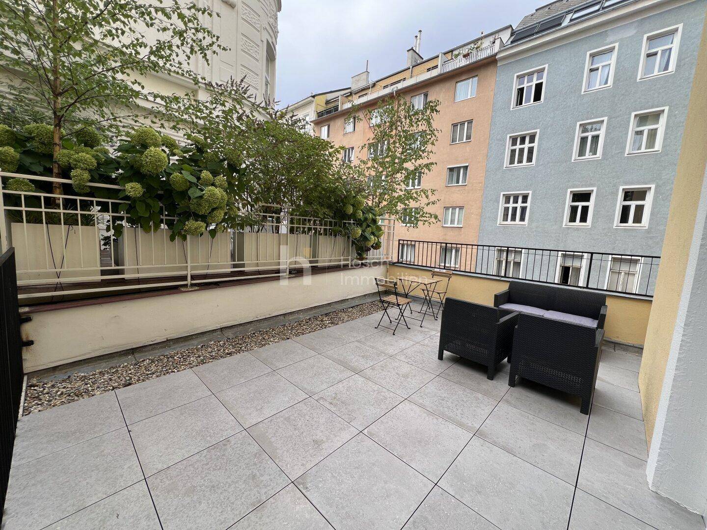 Geräumige Terrasse mit modernen Fliesen und Blick auf die umliegenden Gebäude.