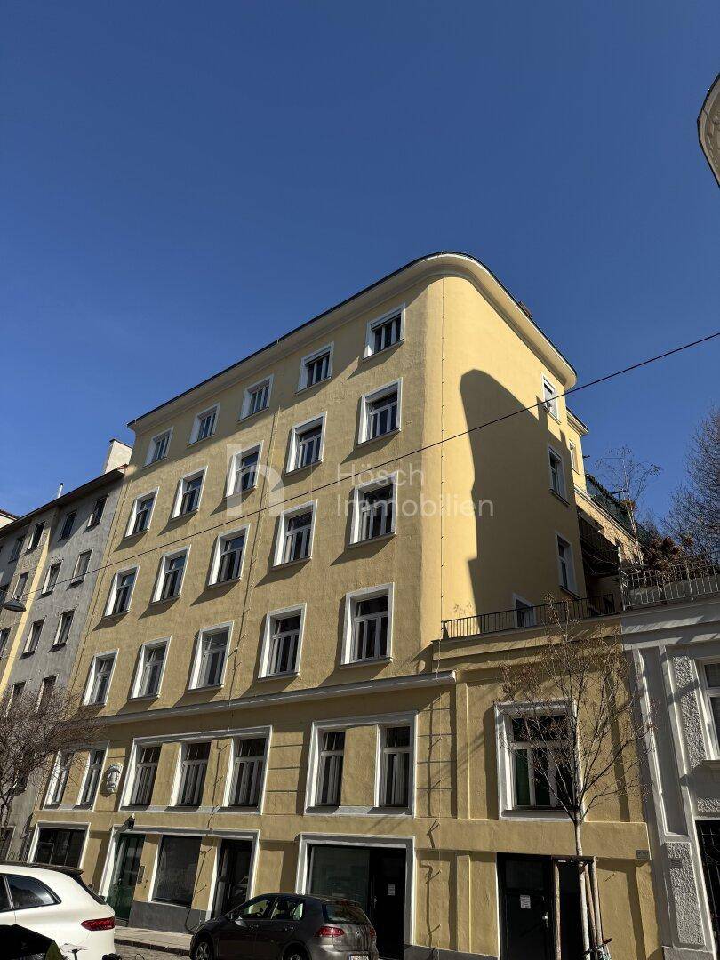 Gelbe Fassade eines Mehrfamilienhauses mit vielen Fenstern und Balkonen.
