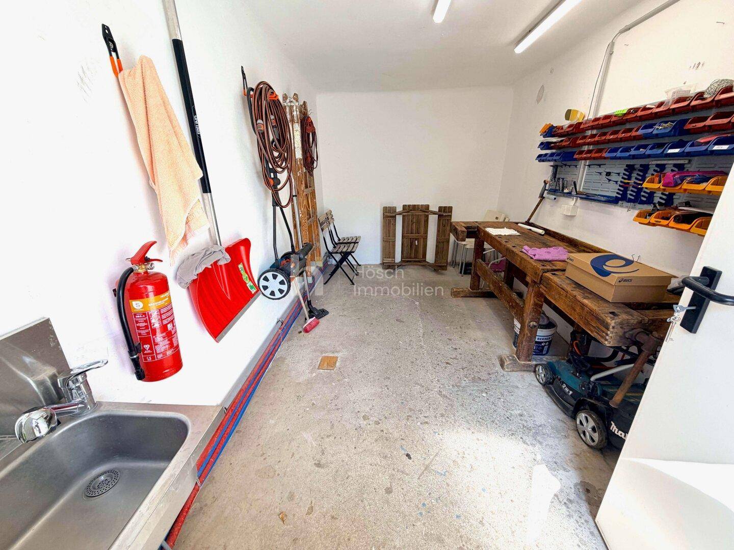 Werkstatt mit Arbeitsbank, Spülbecken und verschiedenen Werkzeugen an der Wand.
