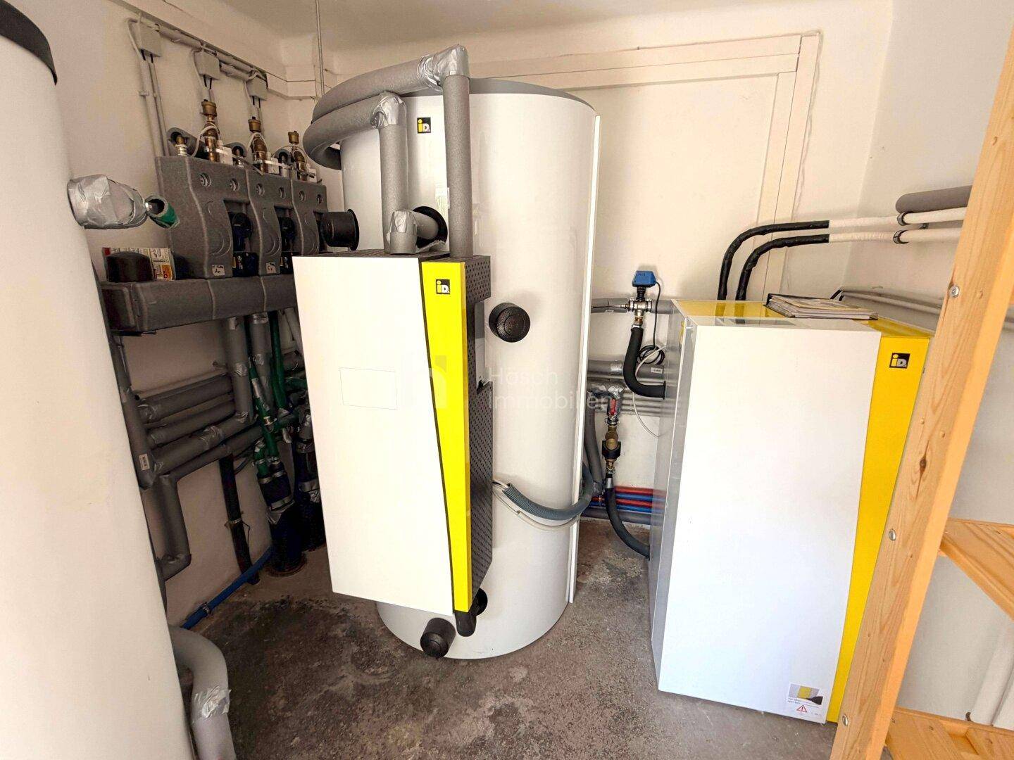Moderne Heizungs- und Warmwasseranlagen in einem sauberen Technikraum mit Regalen.