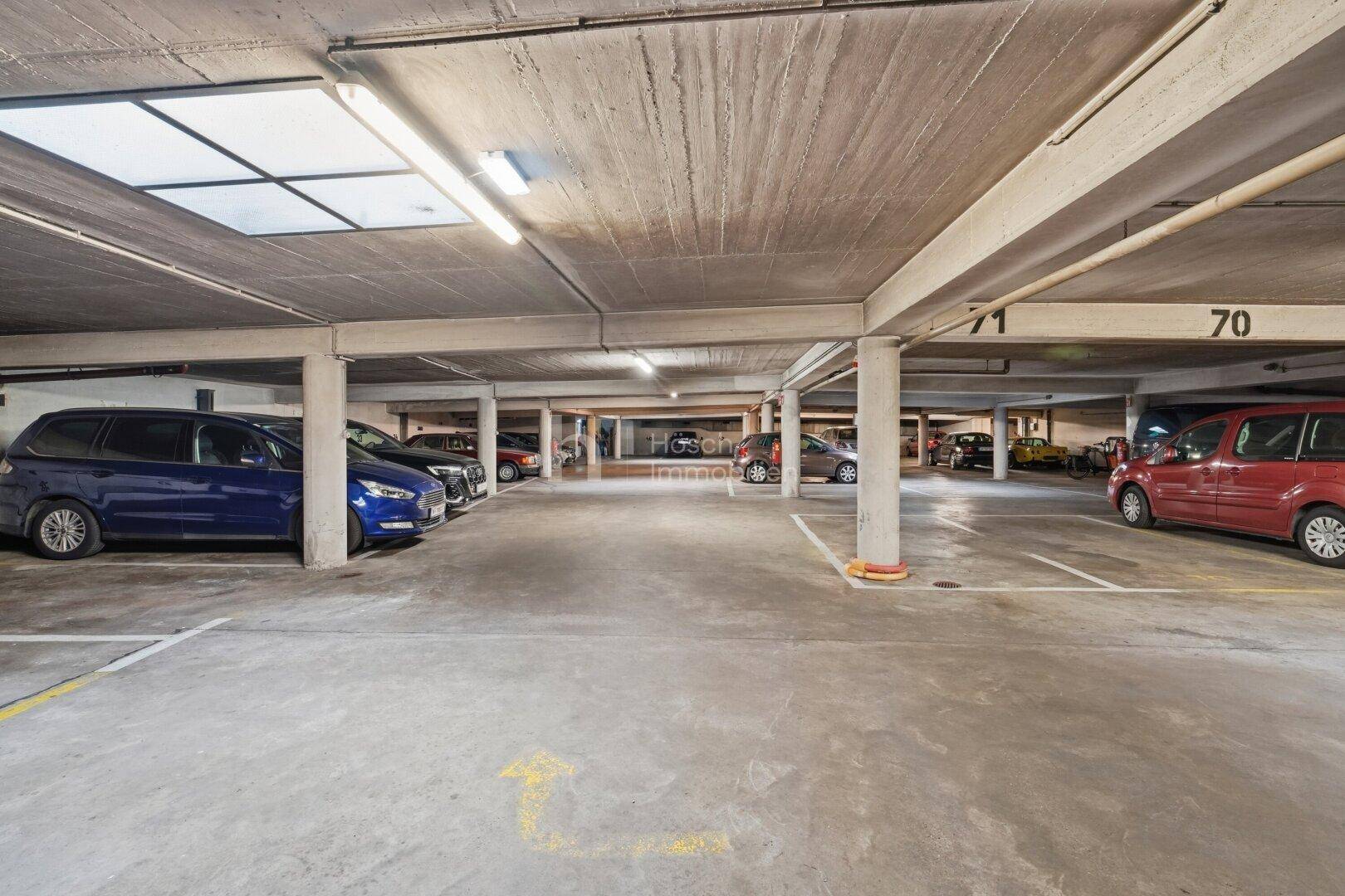 Geräumige Tiefgarage mit vielen Stellplätzen und guter Beleuchtung für Fahrzeuge.