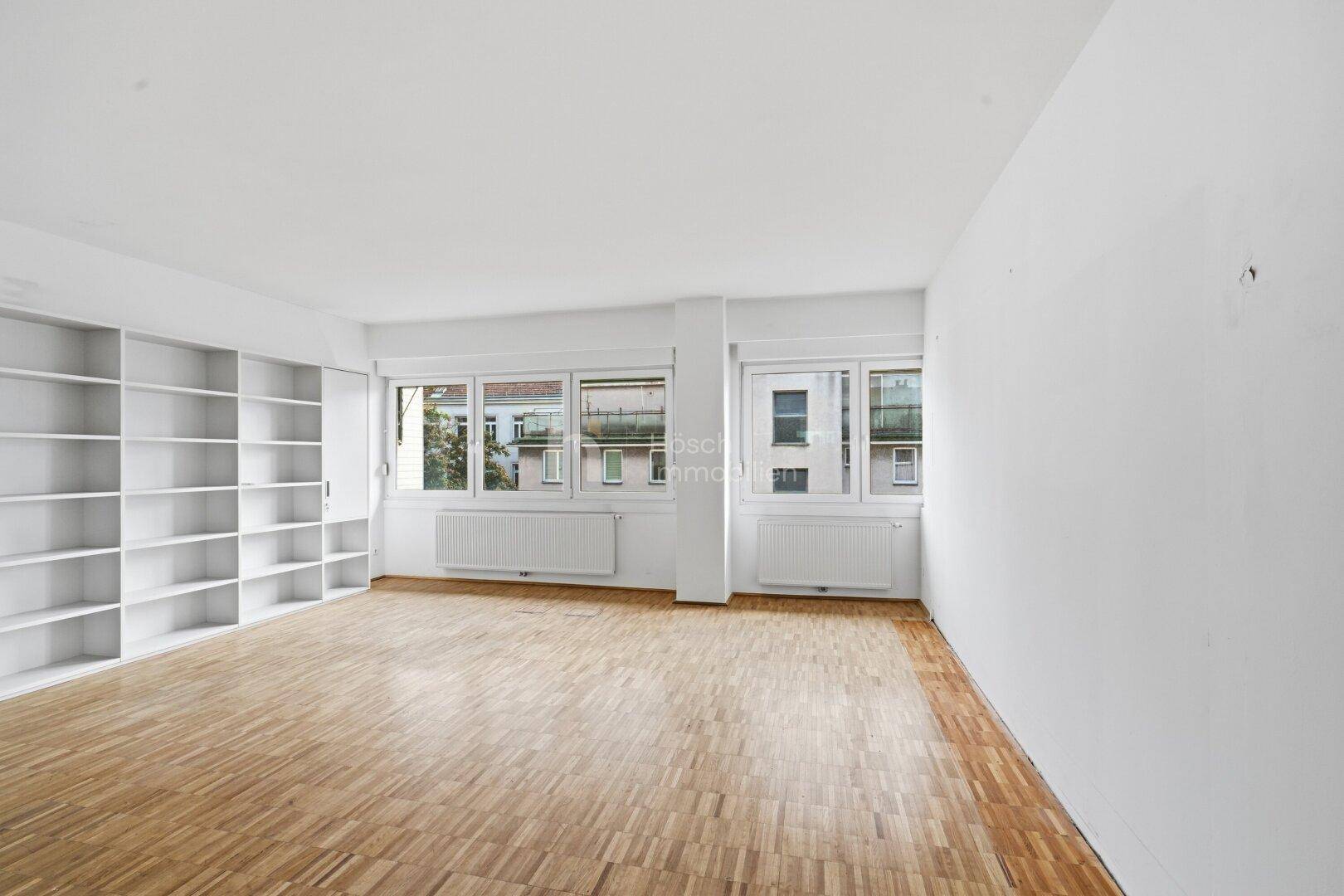 Helles Zimmer mit Parkettboden und Einbauregalen, bereit für individuelle Gestaltung.