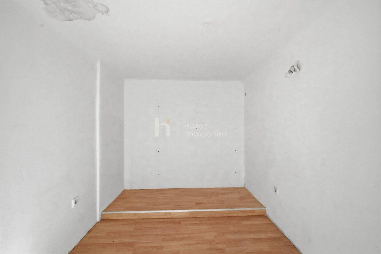 Leerer Raum mit erhöhtem Bereich und Holzboden, bietet Potenzial für verschiedene Nutzungen.