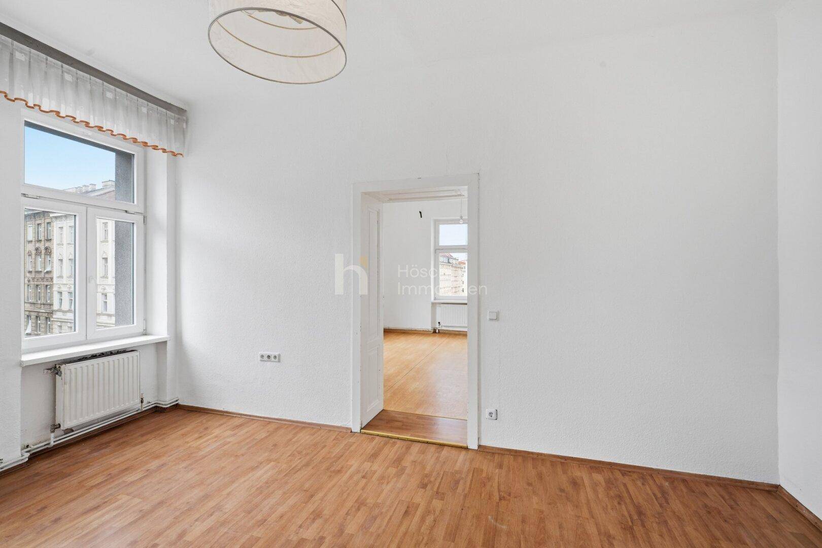 Helles Zimmer mit Laminatboden und einem Fenster, das einen Blick auf die Stadt bietet, mit Zugang zu einem weiteren Raum.