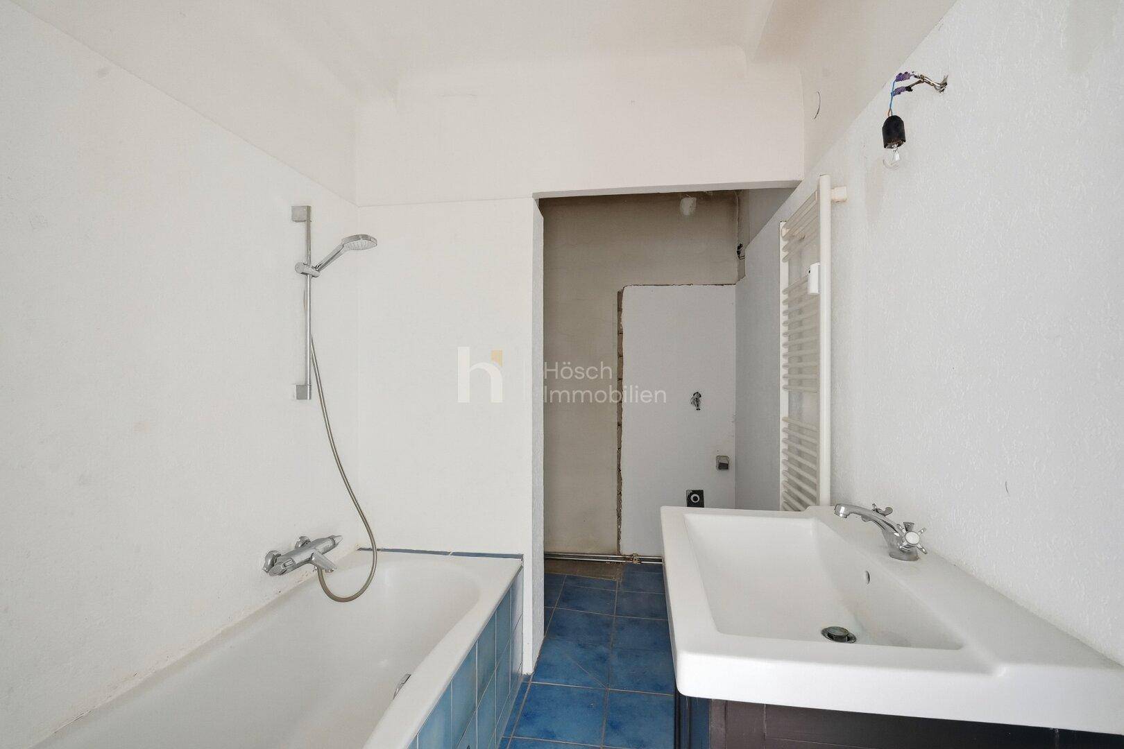 Badezimmer im Rohzustand mit Badewanne, Waschbecken und beheiztem Handtuchhalter.
