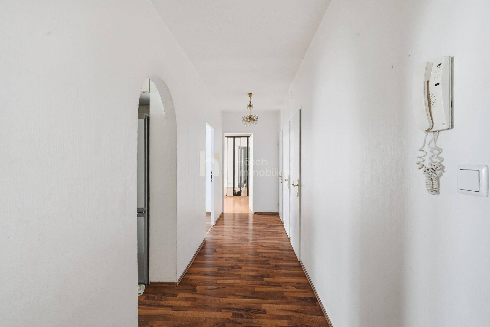 Langer Flur mit Laminatboden und Gegensprechanlage.
