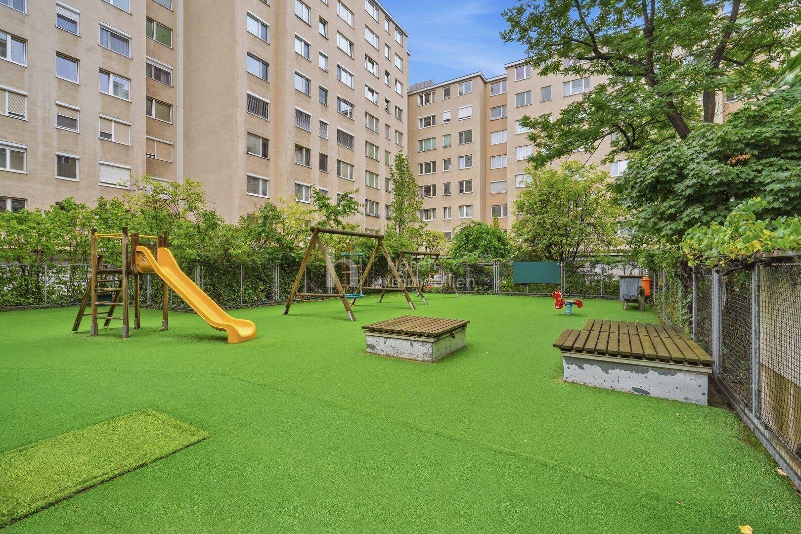Kinderspielplatz mit Rutsche und Schaukeln in einer Wohnanlage.