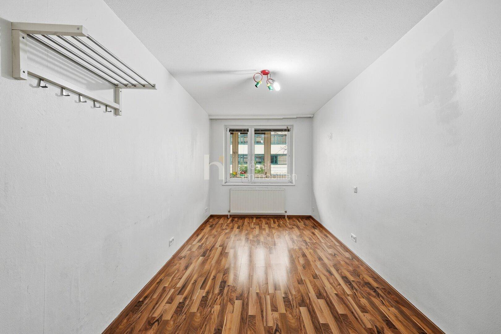 Kleineres Zimmer mit Laminatboden und Fenster, ideal als Kinder- oder Arbeitszimmer.
