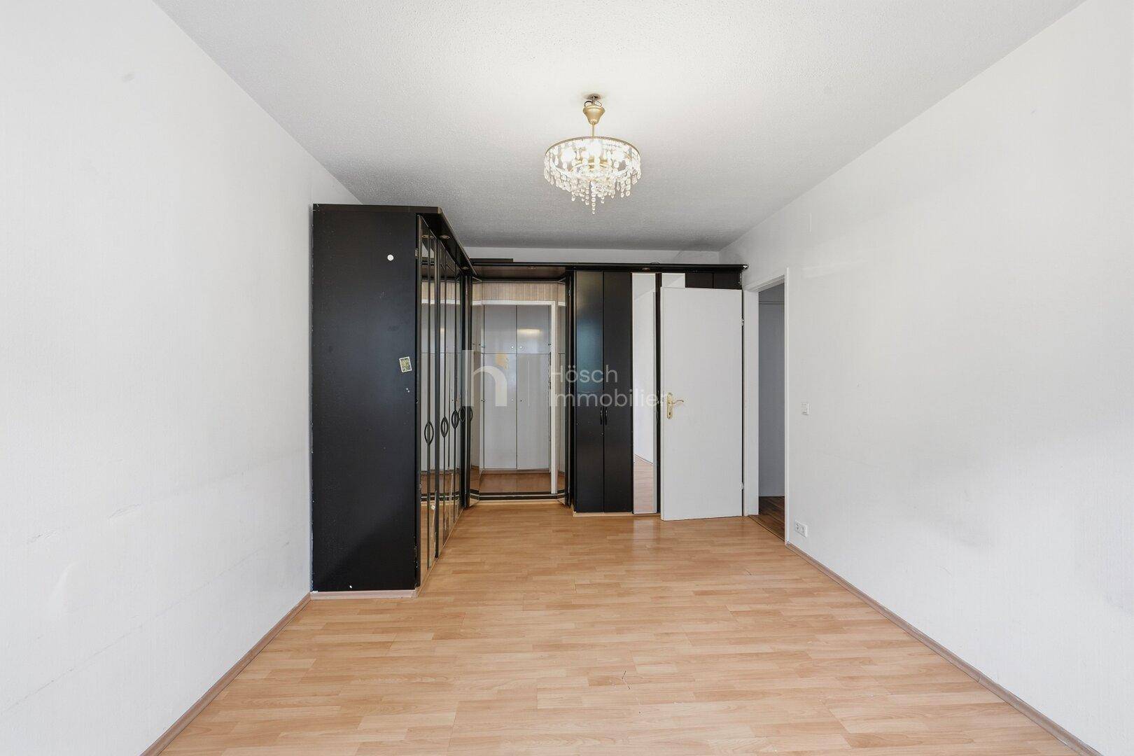 Geräumiges Schlafzimmer mit Laminatboden und großen Einbauschränken.