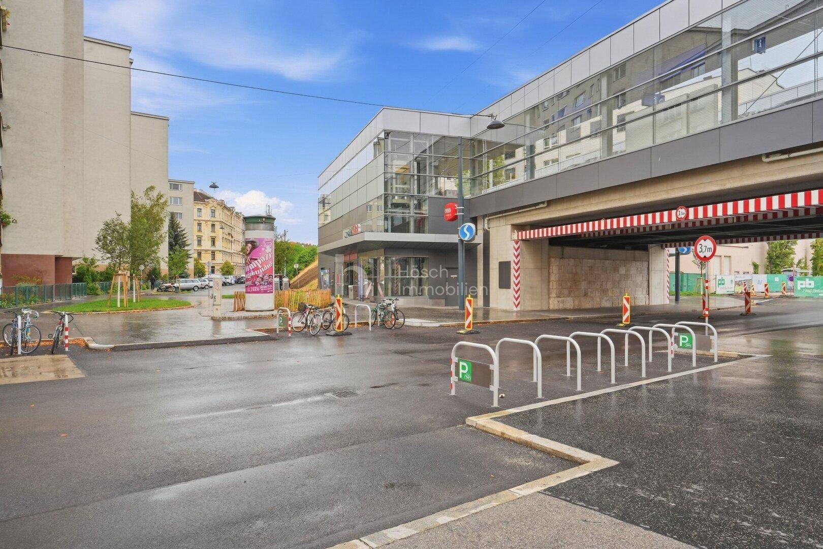 Städtische Umgebung mit Gebäuden, Parkplätzen und einer Haltestelle.