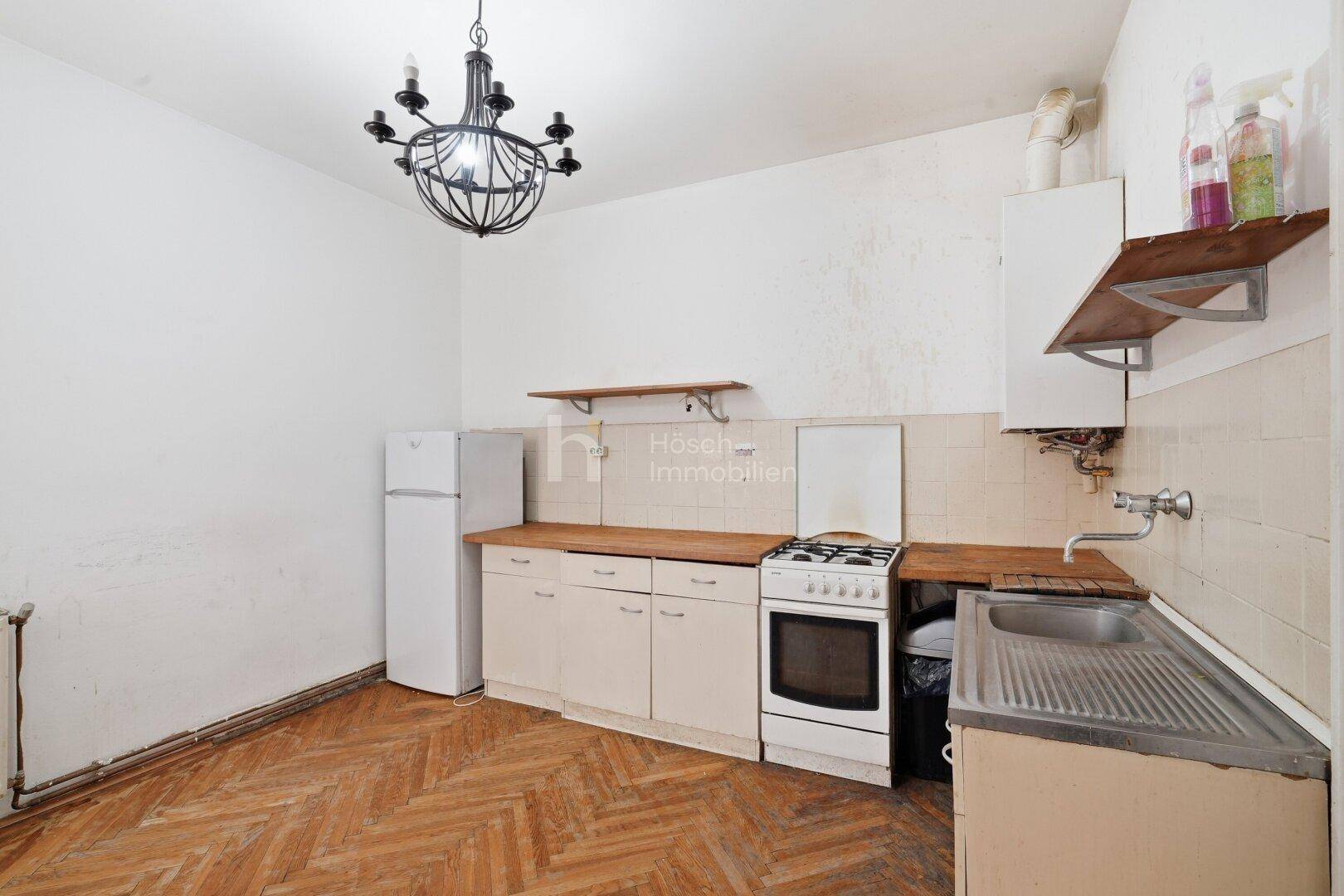 Einfache Küche mit Gasherd, Kühlschrank und Holz-Arbeitsplatten, bereit zur Modernisierung.