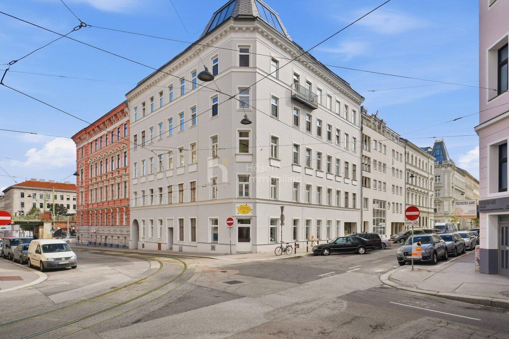 Historisches Eckgebäude mit klassischer Architektur und Mansarddach in urbaner Umgebung.