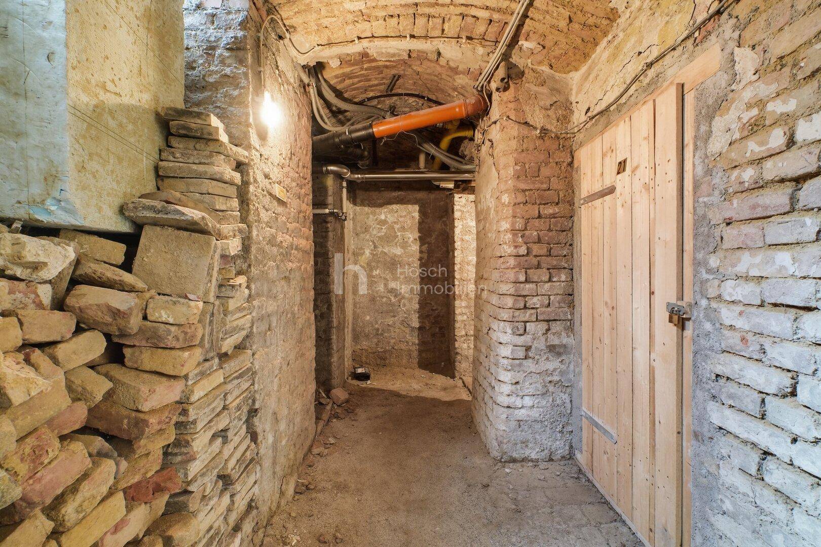 Historischer Kellerraum mit unverputzten Ziegelwänden, Gewölbedecke und Holztüren.