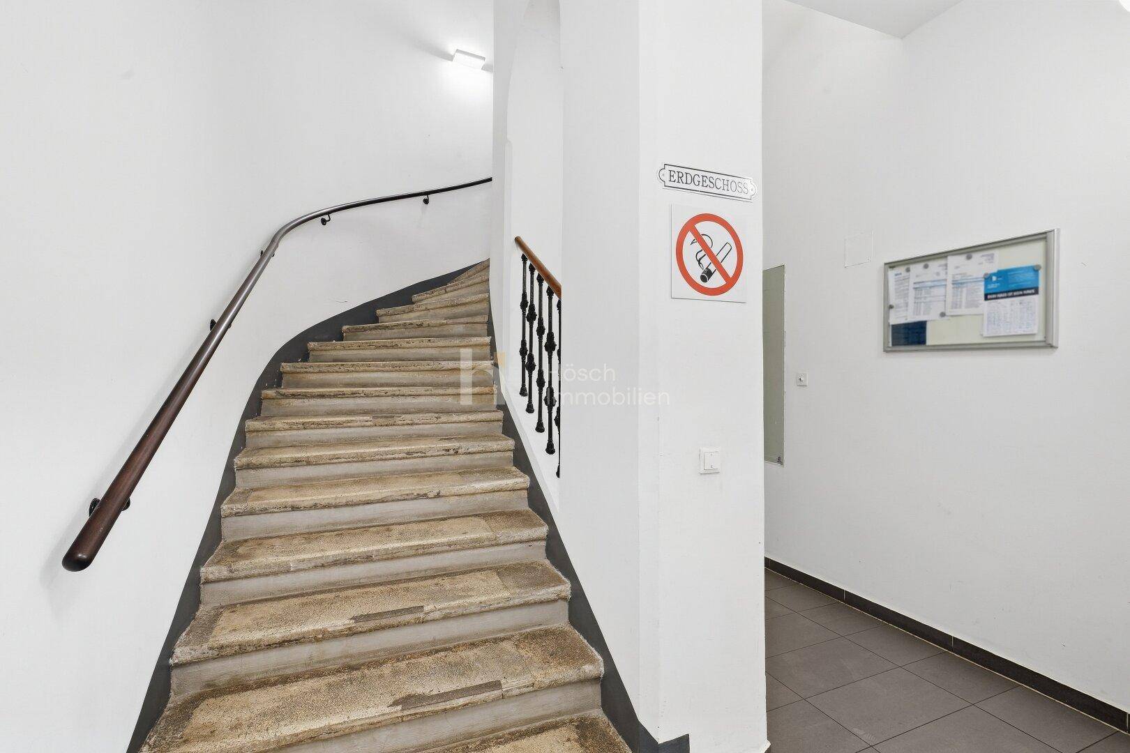 Historisches Treppenhaus mit abgenutzten Steinstufen und einem schmiedeeisernen Geländer.