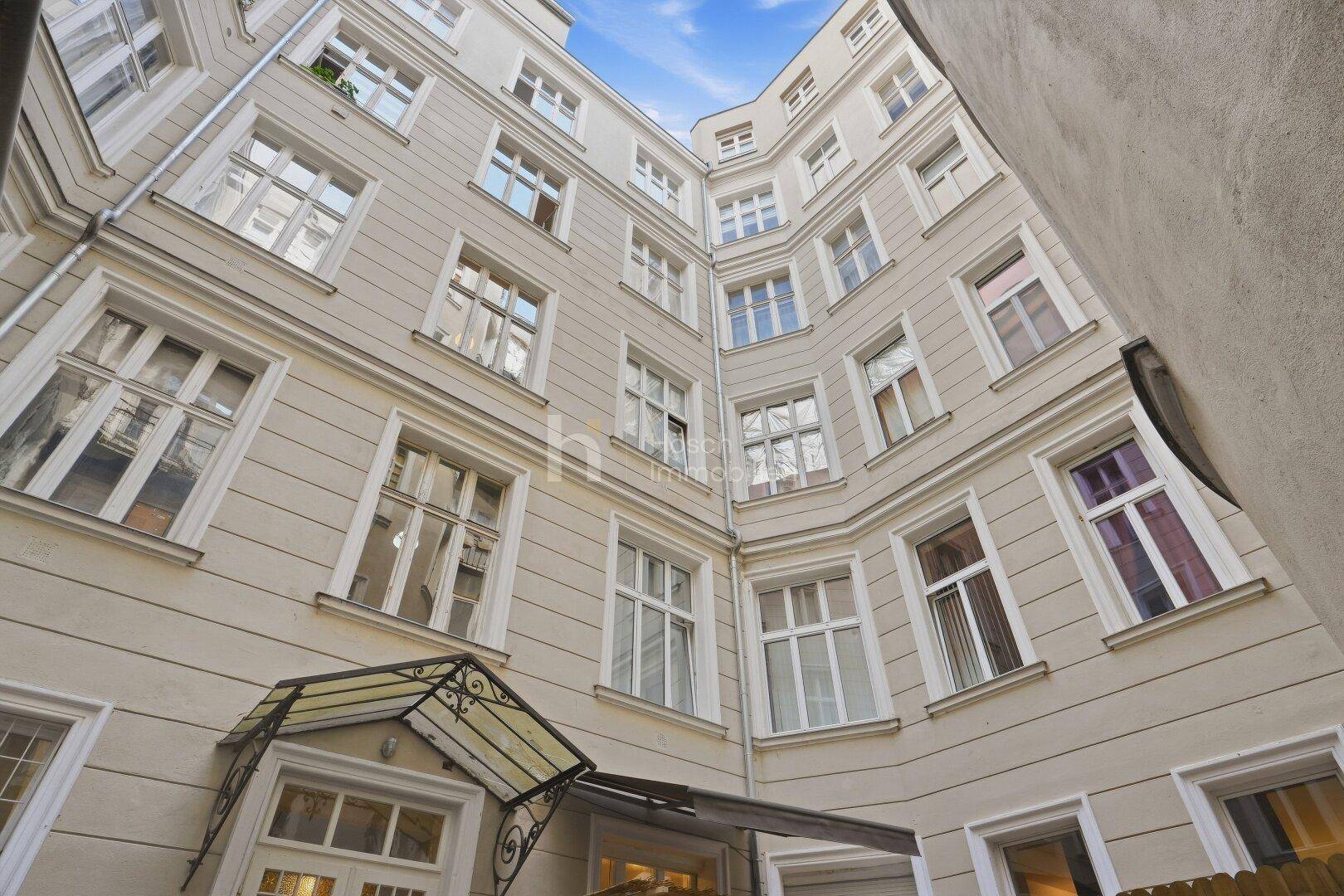 Innenhof eines Altbaus mit vielen Fenstern und klassischer Architektur, die viel Licht hereinlässt.