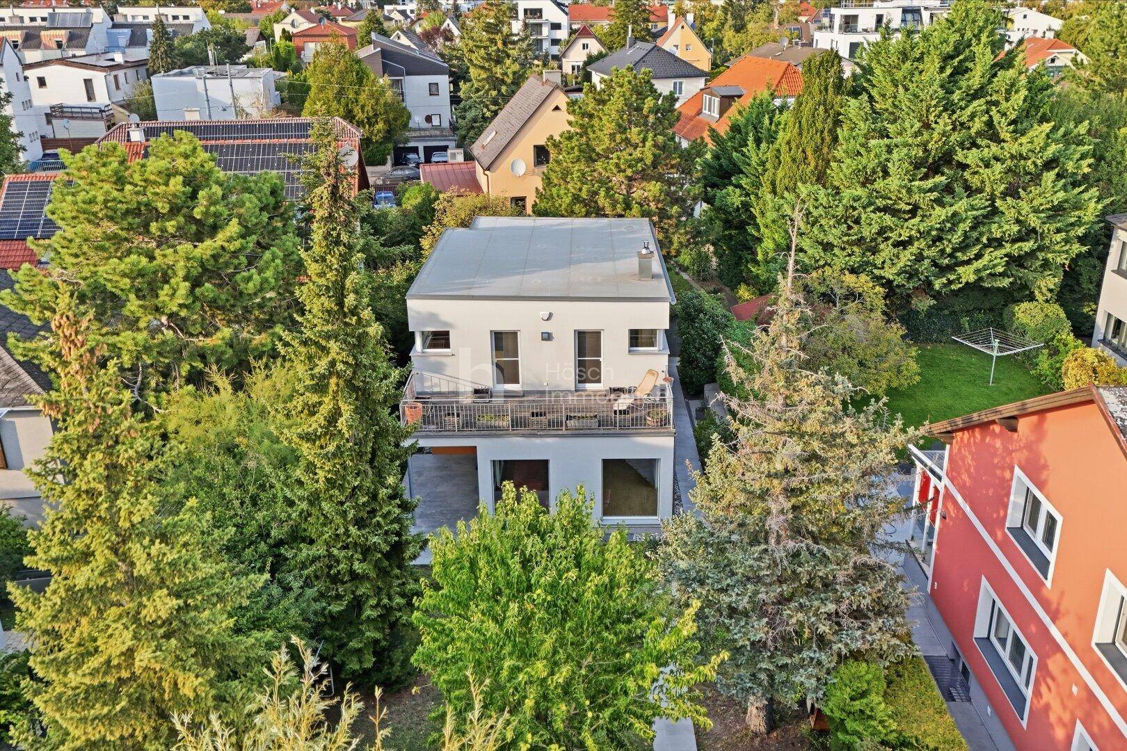 Luftaufnahme des modernen Hauses, eingebettet in eine grüne Wohnsiedlung.