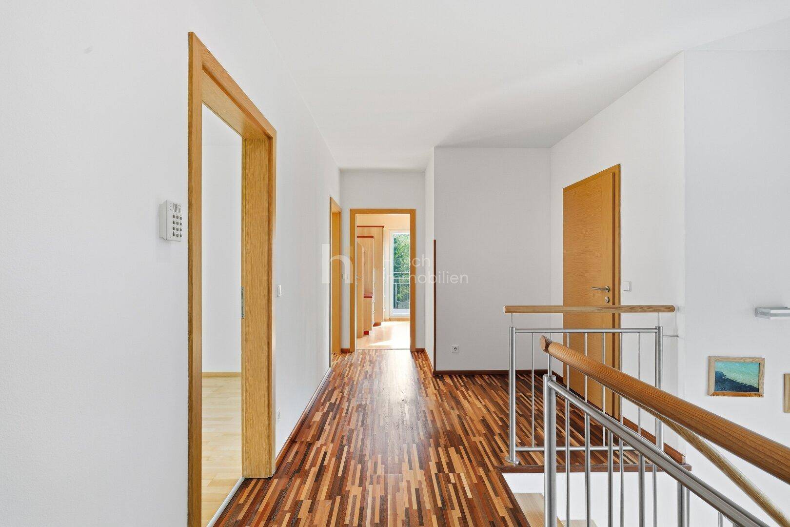 Heller Flur im Obergeschoss mit Holzboden und modernem Treppengeländer.