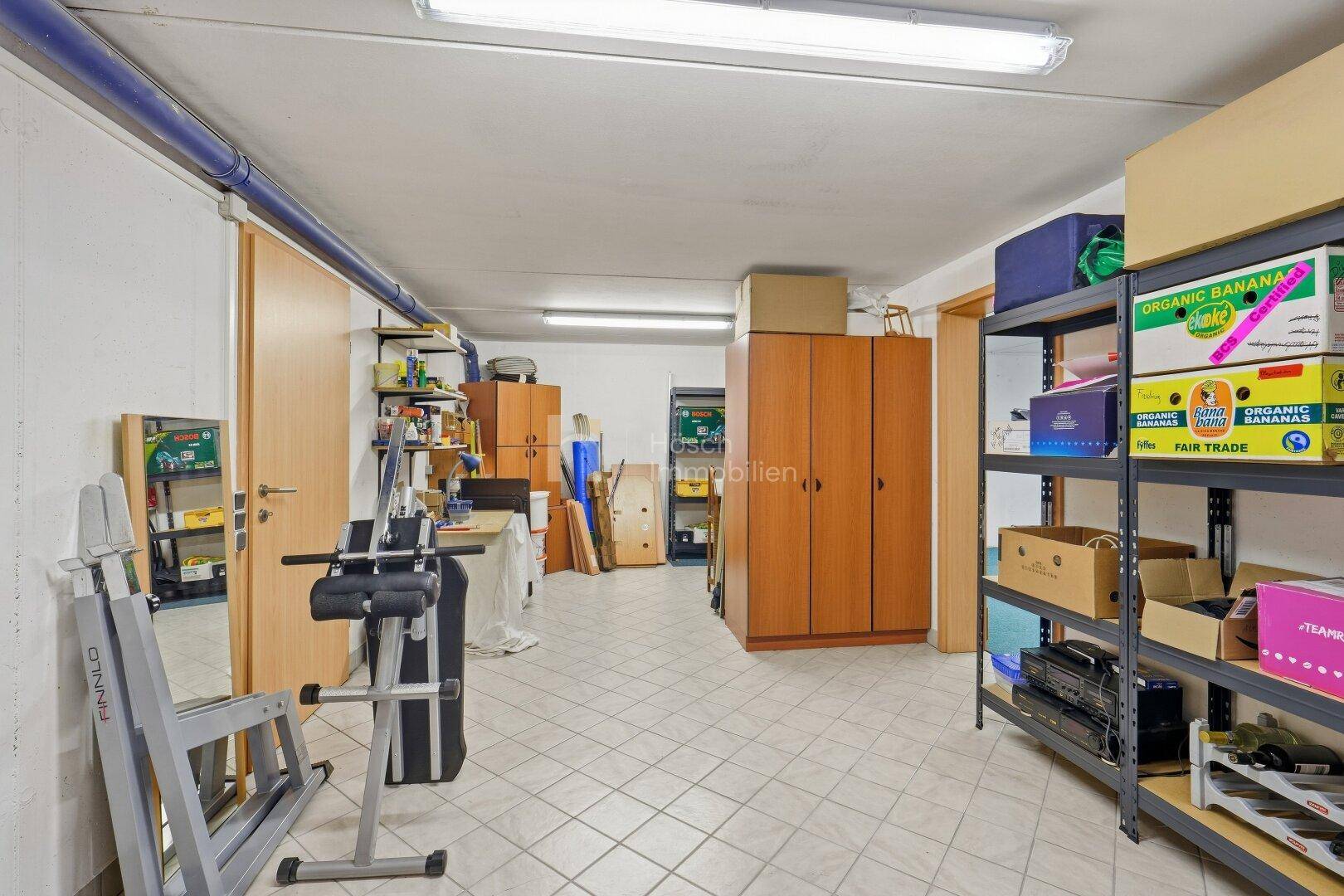 Praktischer Abstellraum im Keller mit Fliesenboden, Regalen und Stauraum.