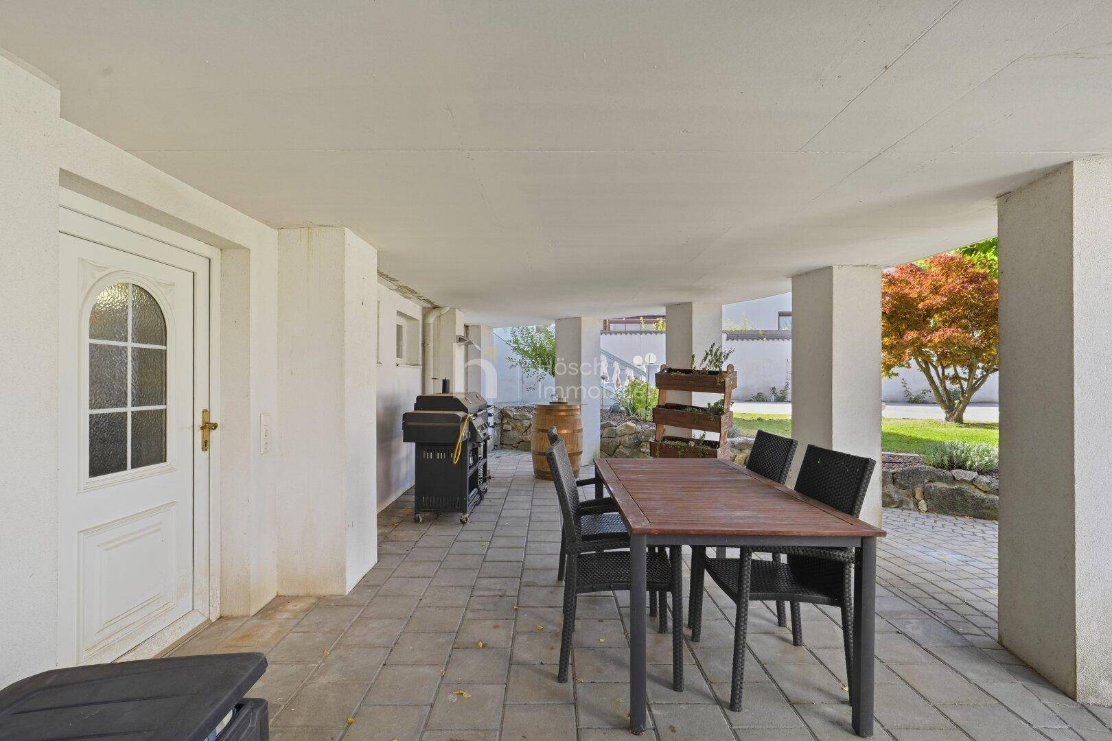 Überdachte Terrasse mit Essbereich und Grillstation, ideal für Mahlzeiten im Freien.