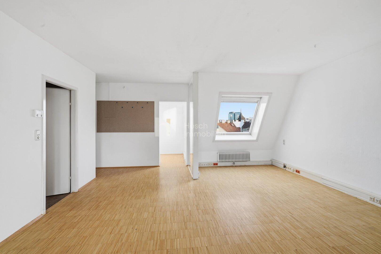 Heller Raum im Dachgeschoss mit Holzboden, Dachfenster und mehreren Türen, vielseitig nutzbar.
