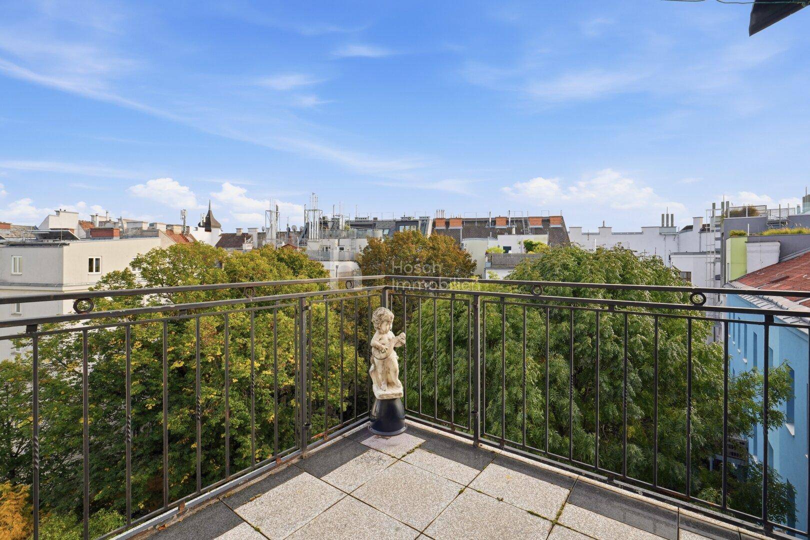 Balkon mit schmiedeeisernem Geländer, Fliesenboden und Blick über die Dächer der Stadt.