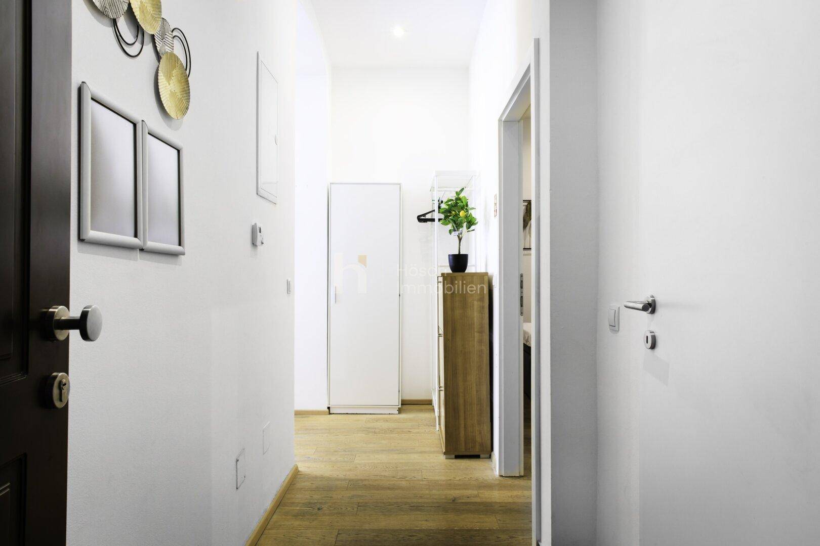 Heller Flur mit Holzfußboden, Garderobe und Zugang zu verschiedenen Räumen.