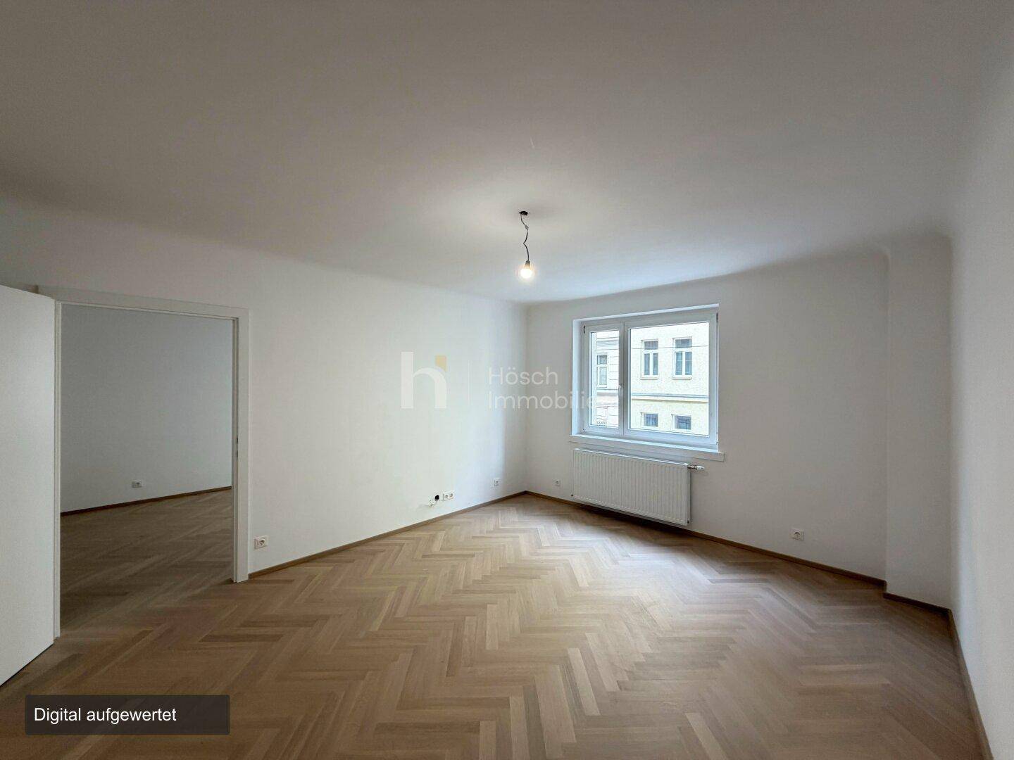 Geräumiges, helles Zimmer mit klassischem Fischgrätparkett und Blick nach draußen.