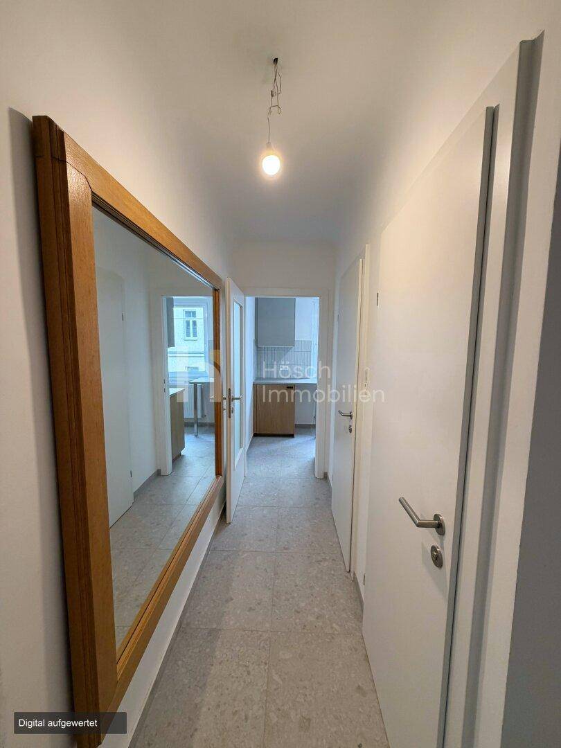 Heller Flur mit großem Holzspiegel und Zugang zu verschiedenen Zimmern der Wohnung.