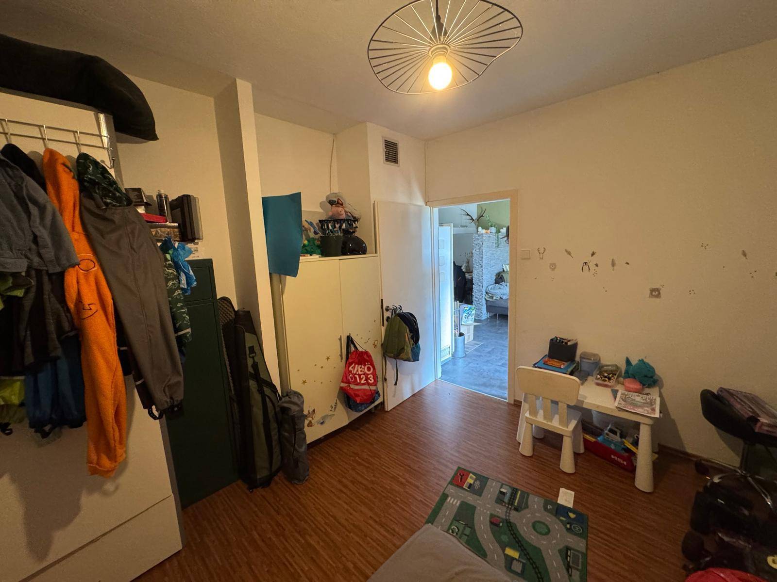 Kinderzimmer mit Spielbereich, Kleiderstange und Blick in den Flur.