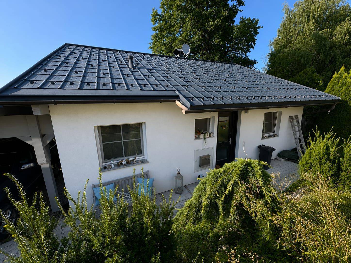 Das Einfamilienhaus präsentiert sich mit einem modernen Ziegeldach und einer hellen Fassade umgeben von Grün.