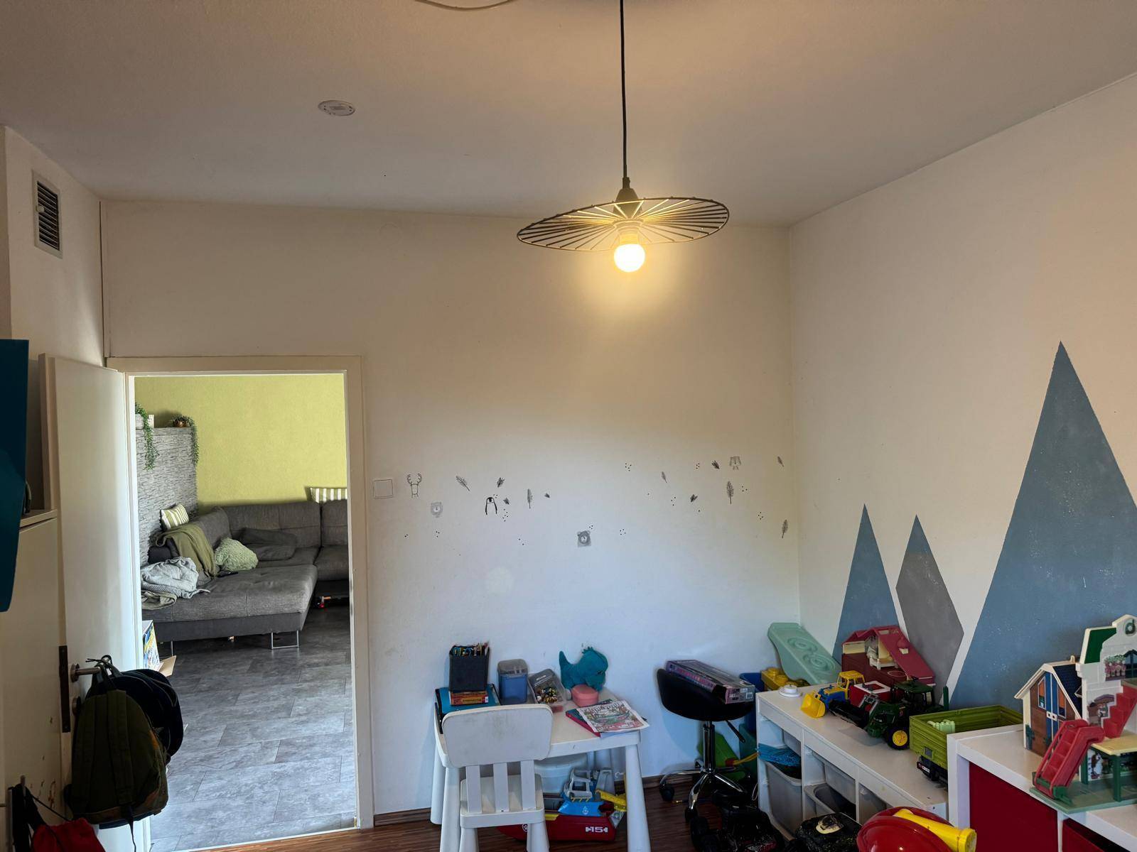 Kinderzimmer mit kreativer Bergwandmalerei und Blick in den angrenzenden Raum.