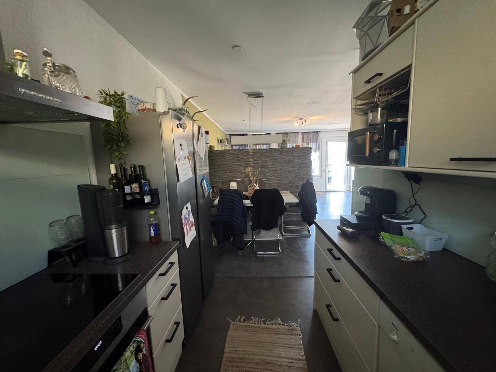 Moderne Küche mit dunkler Arbeitsplatte und Blick auf den angrenzenden Essbereich.
