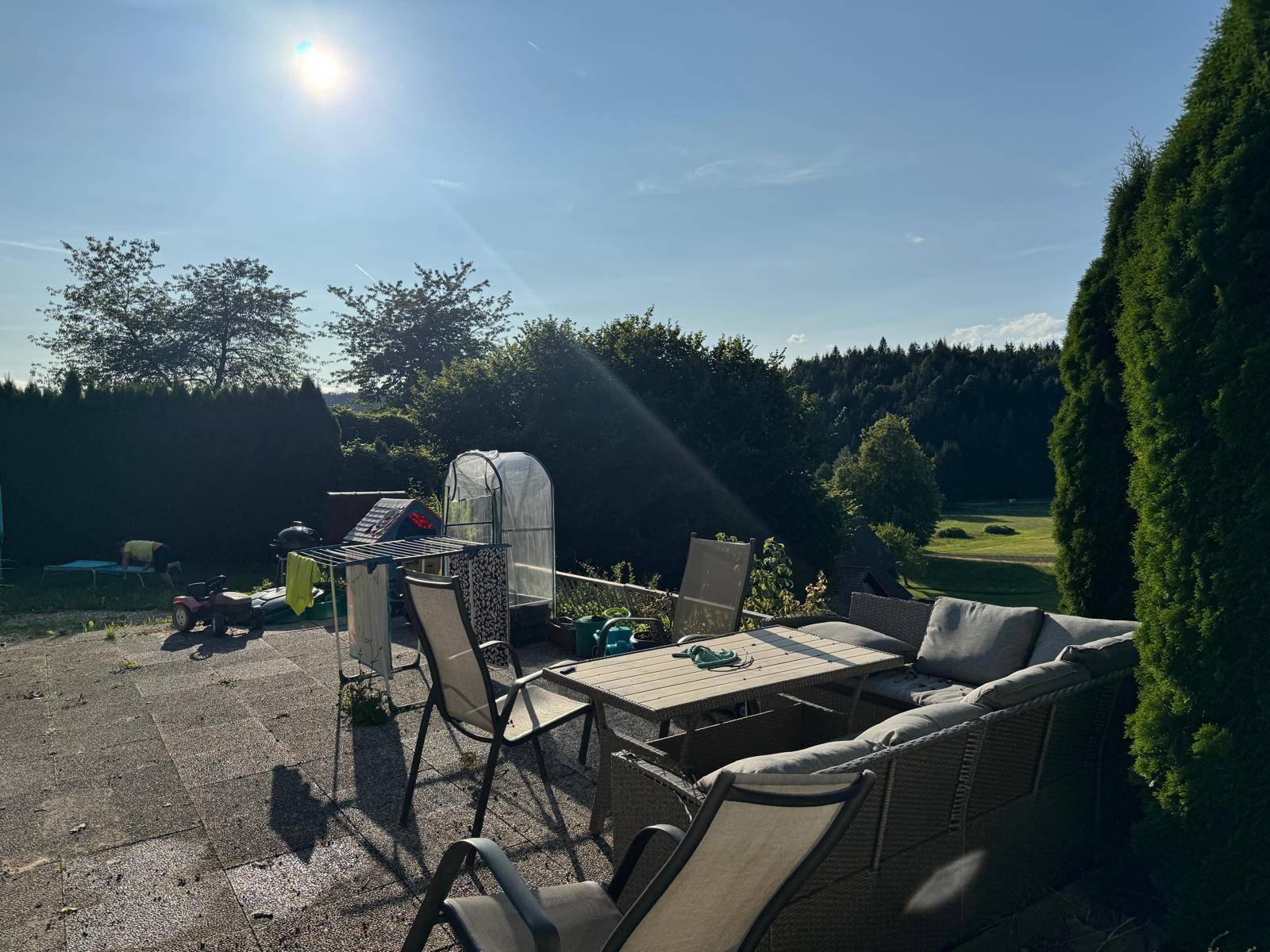 Sonniger Terrassenbereich mit bequemen Sitzgelegenheiten und Blick auf die Natur und den Garten.