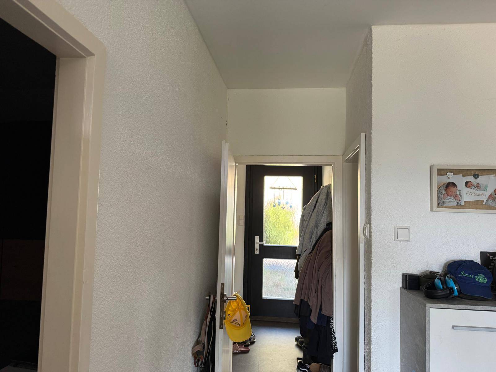 Eingangsbereich mit Garderobe und Blick zur Haustür, die viel Tageslicht hereinlässt.