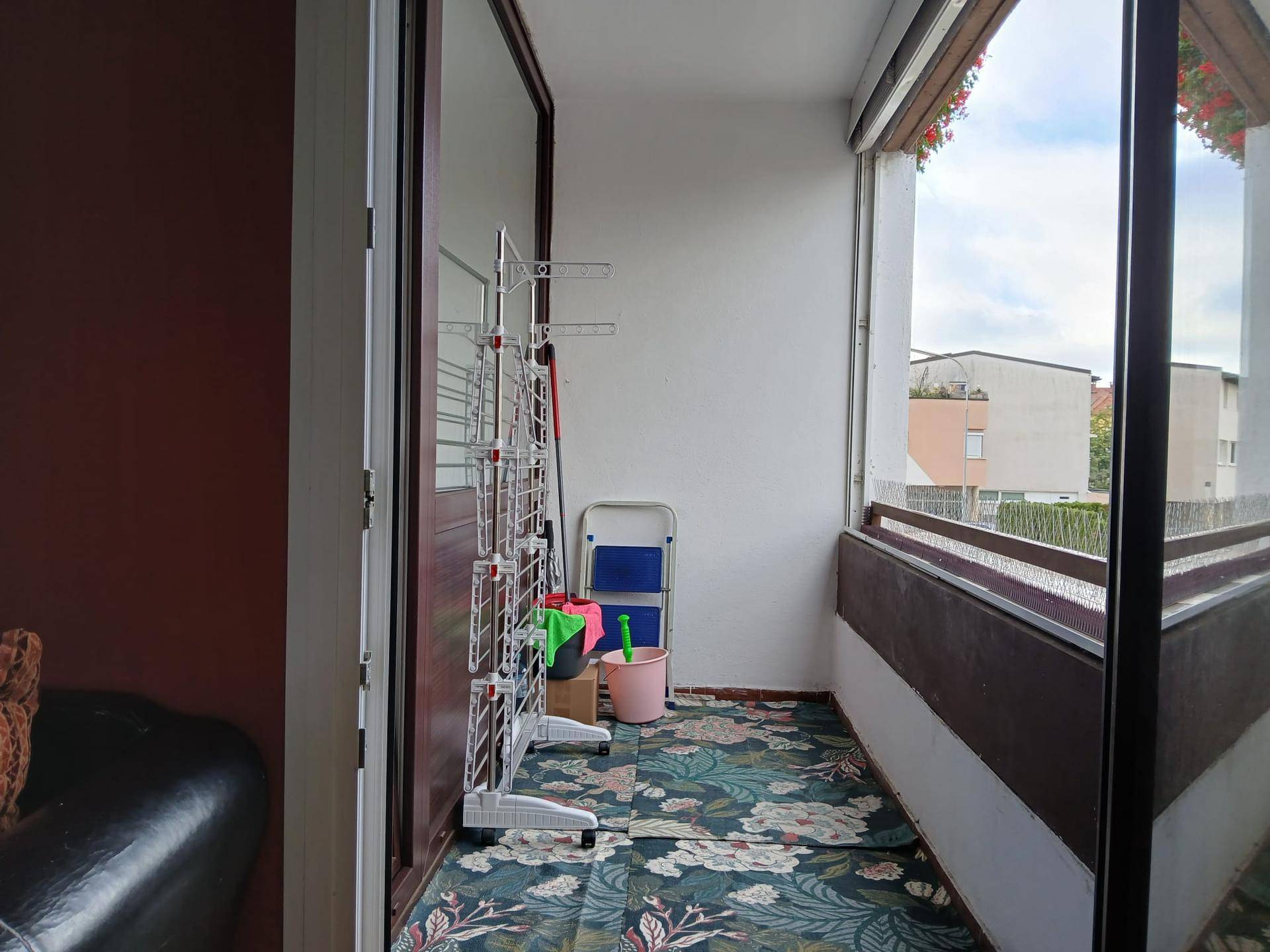 Überdachter Balkon mit Wäscheständer und Blick auf die umliegenden Gebäude. Ein praktischer Außenbereich.