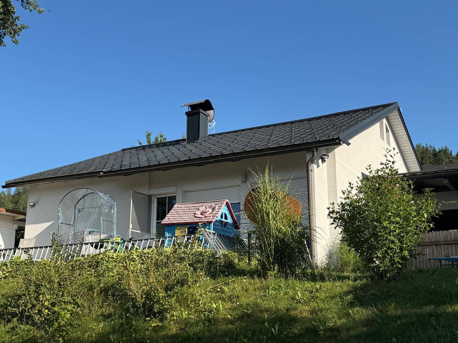 Das Haus von hinten mit einer Terrasse und weitem Blick über die umliegende Natur.