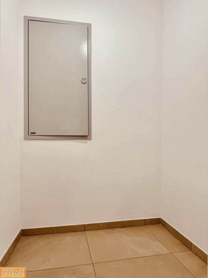 Praktischer Abstellraum mit Fliesenboden und einem Wandschrank für zusätzlichen Stauraum.