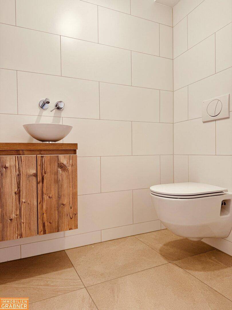 Modernes Gäste-WC mit Holzwaschtisch, Einzelwaschbecken und wandhängender Toilette.