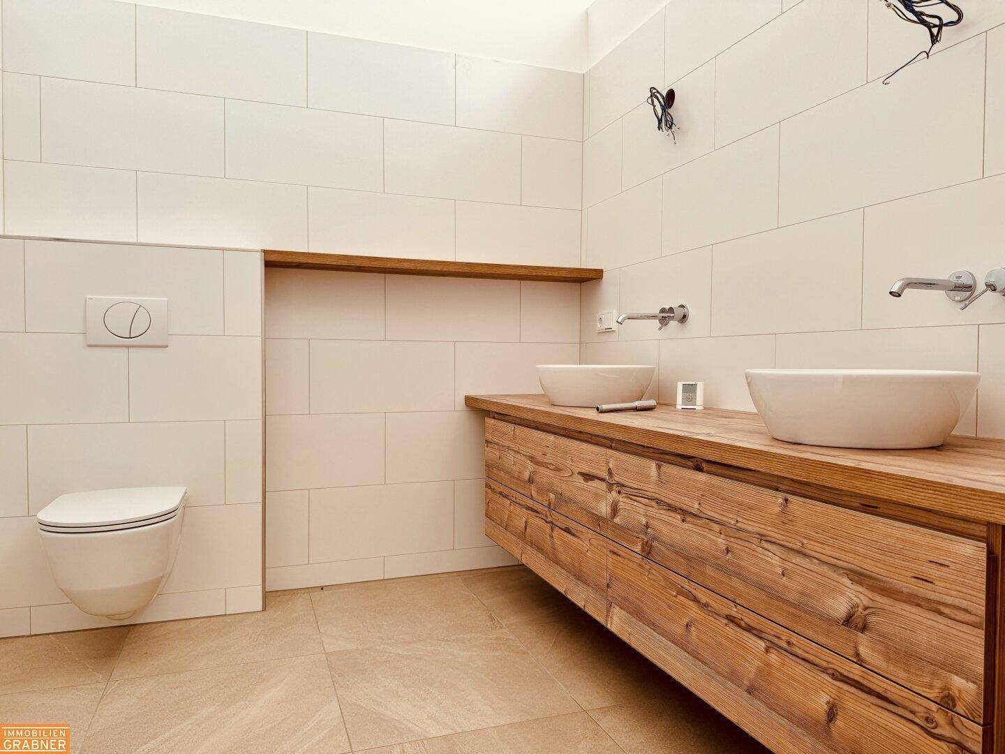 Modernes Badezimmer mit Doppelwaschbecken auf Holzunterschrank und wandhängendem WC.