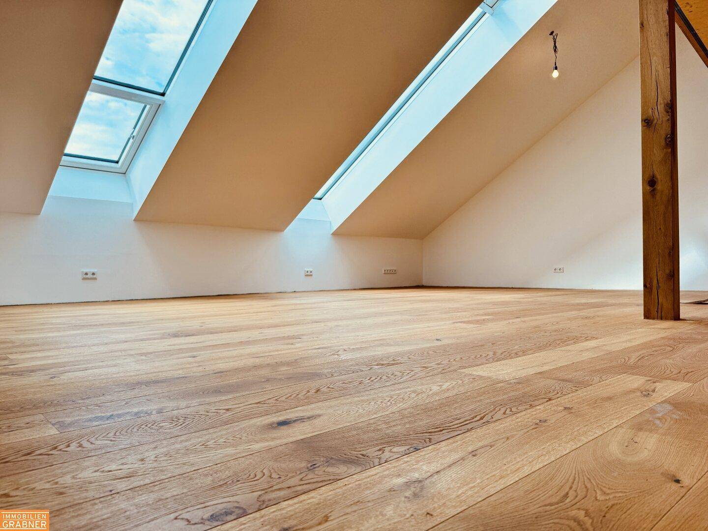 Heller Dachbodenraum mit Holzboden und großen Dachfenstern, bereit für die Gestaltung.