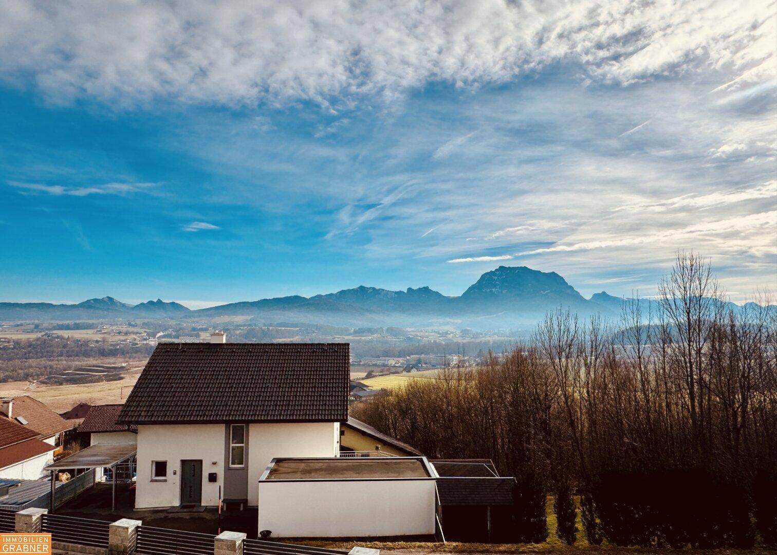 Einfamilienhaus mit Satteldach und weitem Blick auf die umliegende Landschaft und Berge.